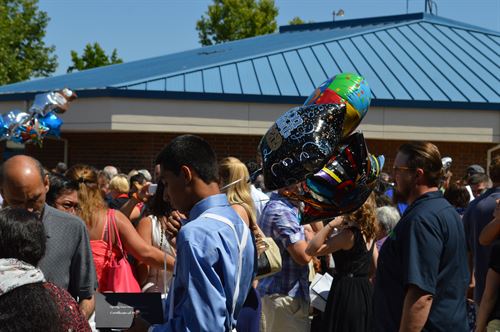 people standing outdoors, person in foreground holds balloons